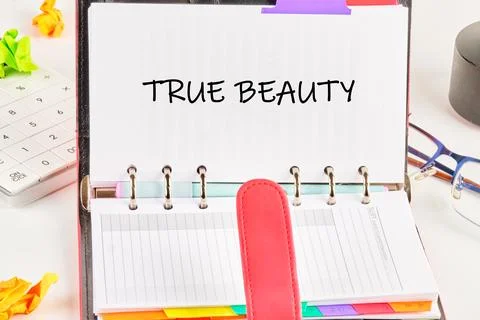 A personal planner is opened on a bright desk, displaying the words true beau Stock Photos