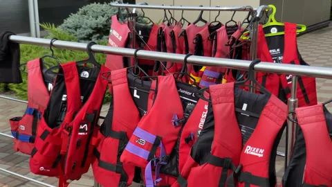 Personal red life jackets in store. Many life jackets hang in a row on hanger Stock Footage 159595102