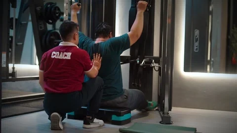 Personal trainer coaching client doing lat pulldown Stock Footage 346473926