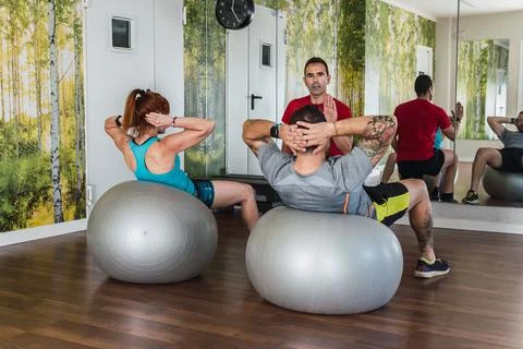 Personal trainer explaining pilates exercises to people indoors Stock Photos