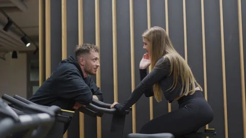 Personal Trainer Flirting With Client on Stationary Bike 스톡 동영상 346485472