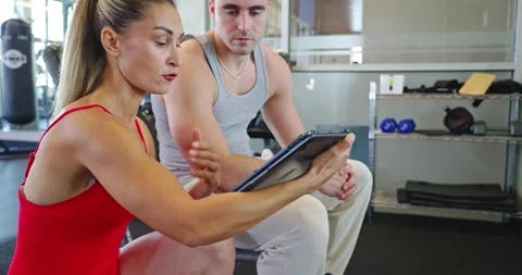 Personal Trainer Guiding Client with Tablet in Gym Stock Footage 323773249