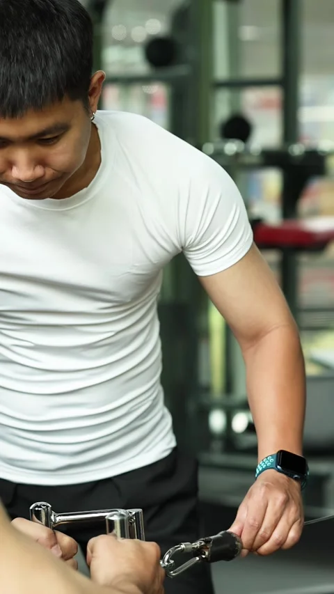 Personal Trainer Guiding Seated Cable Row Exercise in Gym Stock Footage 328566236