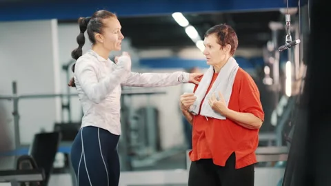 Personal trainer instructing an elderly woman at the gym Stock Footage 330547829