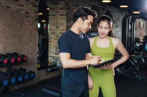 Personal trainer looking at digital tablet and explaining progress to young w 写真素材