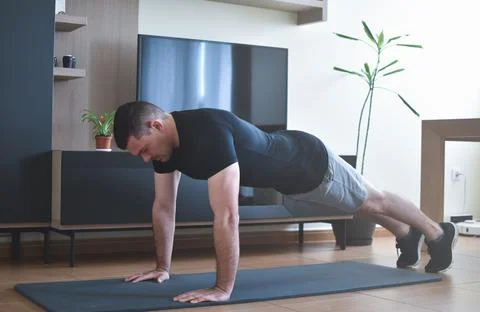 Personal trainer men doing push-ups for a online lesson at home with a pc Stock Photos