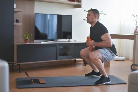 Personal trainer men doing squads exercises for a lesson at home Stock Photos