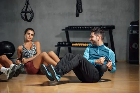 Personal trainer showing how to do twists abs exercise with kettlebell in gym Stock Photos