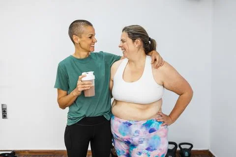 Personal trainer supporting client with protein shake after workout Stock Photos