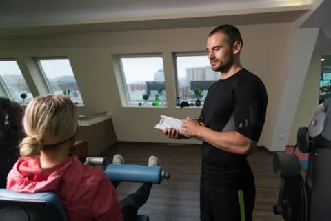 Personal Trainer Takes Notes While Woman Exercising Legs Stock-Fotos