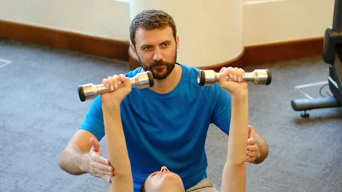 Personal trainer working with client in gym. Trainer man helping young woman 스톡 동영상 131032325