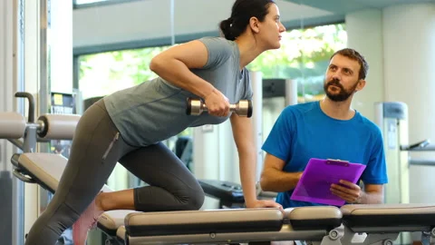 Personal trainer working with client in gym. Trainer man helping young woman 스톡 동영상 131032797