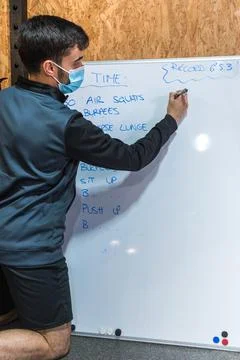 Personal trainer writing exercise chart on a whiteboard Foto stock
