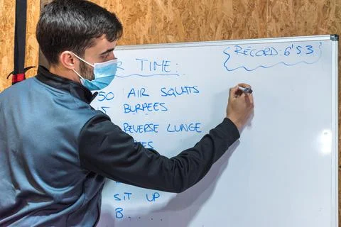 Personal trainer writing exercise chart on a whiteboard Stock Photos