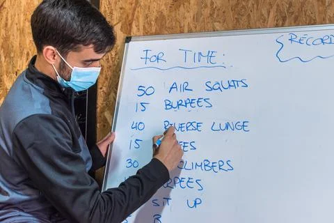 Personal trainer writing exercise chart on a whiteboard Stock Photos