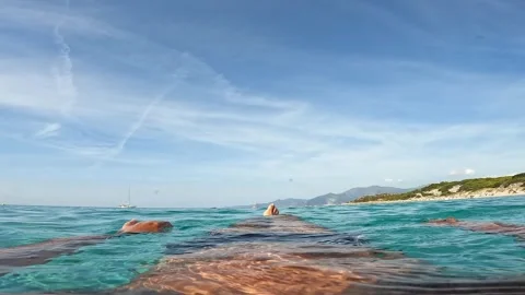 Personal view of legs floating on turquoise sea water of saleccia Stock Footage 279861740