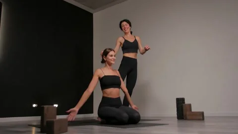 A personal yoga instructor helps a young woman to do an exercise. Yoga class. Video stock 297851027