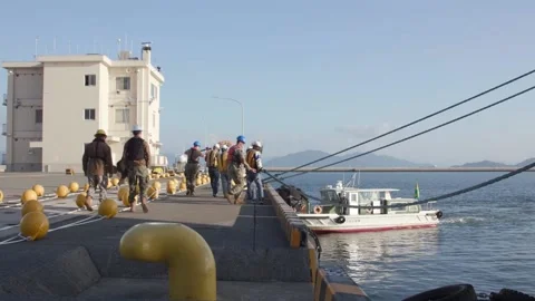 Personnel pulling rope to secure cargo ship at Iwakuni harbour Stock Footage 220780897