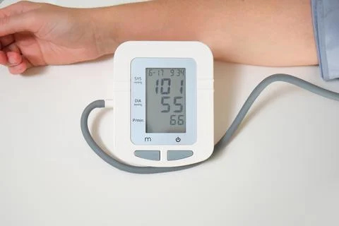 A persons arm is connected to an automatic blood pressure monitor displayin.. Stock Photos