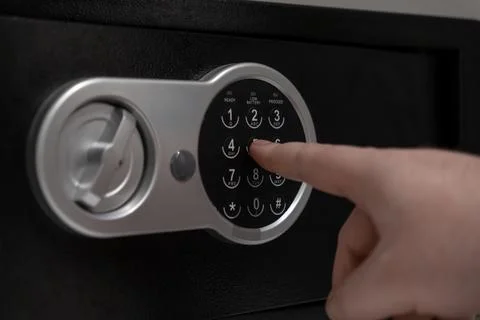Person's finger inputs code on a secure digital safe keypad, ensuring prote.. Stock-Fotos