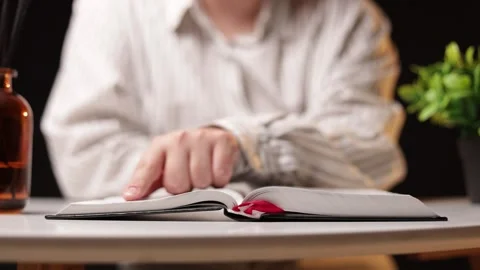 Person's finger tracing text in an open book, close-up on table Stock Footage 339211701