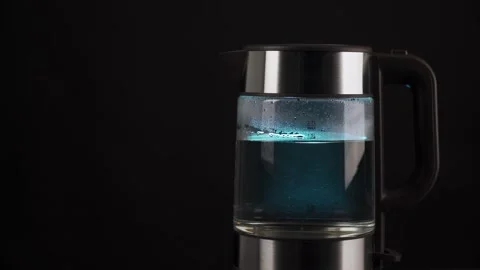 A person's fingers press the button of a glass kettle to boil water. Bubbles are Stock Footage 168357408
