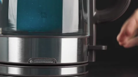 A person's fingers press the button of a glass kettle to boil water. Bubbles are Stock Footage 169149219