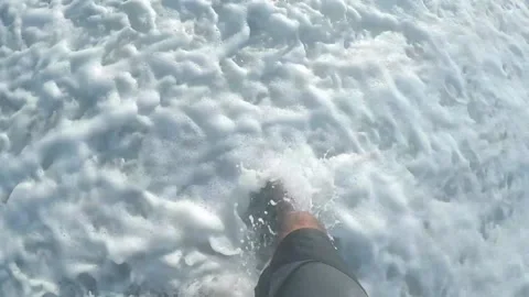 A person's foot while walking on a beach and waves crashing into it Video stock 149056281