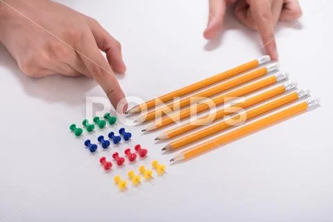 Person's Hand Arranging Pencils And Multi Colored Pushpins Stock Photos