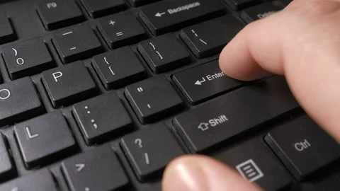 A person's hand carefully presses the Enter key on a computer keyboard Stock Footage 229503463