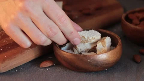 A person's hand carefully takes piece of hard white almond turron from a wood Stock Footage 331379080
