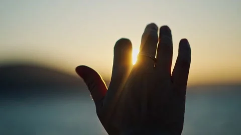 A person's hand catches the sun's rays at the sunset. Stock Footage 237738239