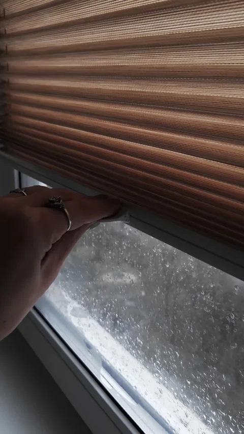 Persons Hand Closing Pleated Blind on a Rainy Day Stock Footage 325223973