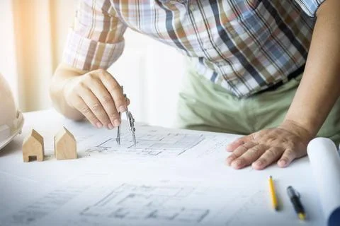 Person's Hand Drawing Plan On Blue Print with architect equipment Fotos de archivo