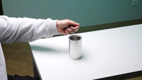 Person's hand dropping a coin into a plain metal can, symbolizing donation Stock Footage 346250055
