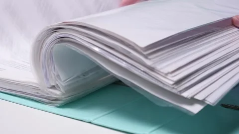 Person's hand flipping through a thick binder filled with numerous white paper Stock Footage 342764329