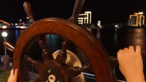 Person's hand gripping ship wheel, navigating han river in da nang at night, Stock Footage 344911870