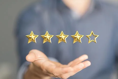 Person's hand holding a digital render of four gold stars out of five Foto stock