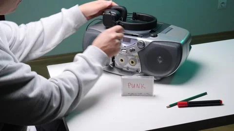 Person's hand holding a headphone cable connected to a vintage boombox playing Stock Footage 345170017
