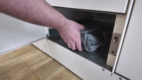 A person's hand inserting a gray package into an open automated parcel lock.. Stock Footage 310902772