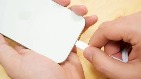 Persons hand inserting a USB cable charger into a Apple iPhone 15 pro. Apple Stock Footage 259940273