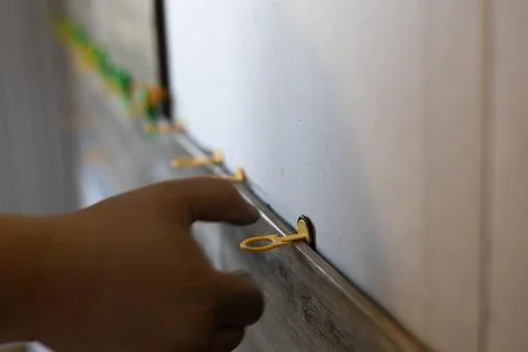 Persons hand installing plastic leveling fastener clips on newly laid wall Stock Photos