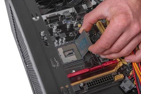 A persons hand installs a central processing unit into a motherboard socket Stock Photos