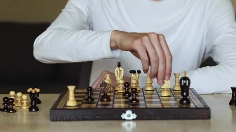 A person's hand moves a chess piece on a wooden board during a game of chess Stock Footage 278900326