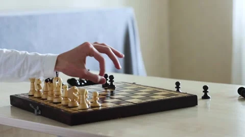 A person's hand moves a chess piece on a wooden chessboard Stock Footage 278900625