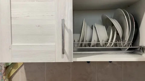 Persons hand opens a modern, light-colored wooden kitchen cabinet, showing clean Stock Footage 316899066