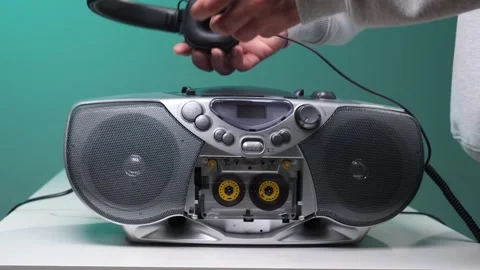 Person's hand operating a classic silver boombox with a clear cassette tape Stock Footage 345530021