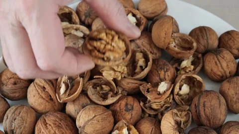Person's hand picking a shelled walnut from a white plate. Stock Footage 328501317