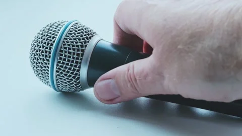 Person's hand picks up microphone from white surface. Perform, song and perform. Stock Footage 247177561