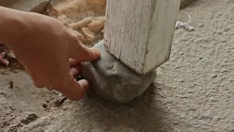 A person's hand placing a large grey stone to prop up a white wooden table .. Stock Footage 324821330